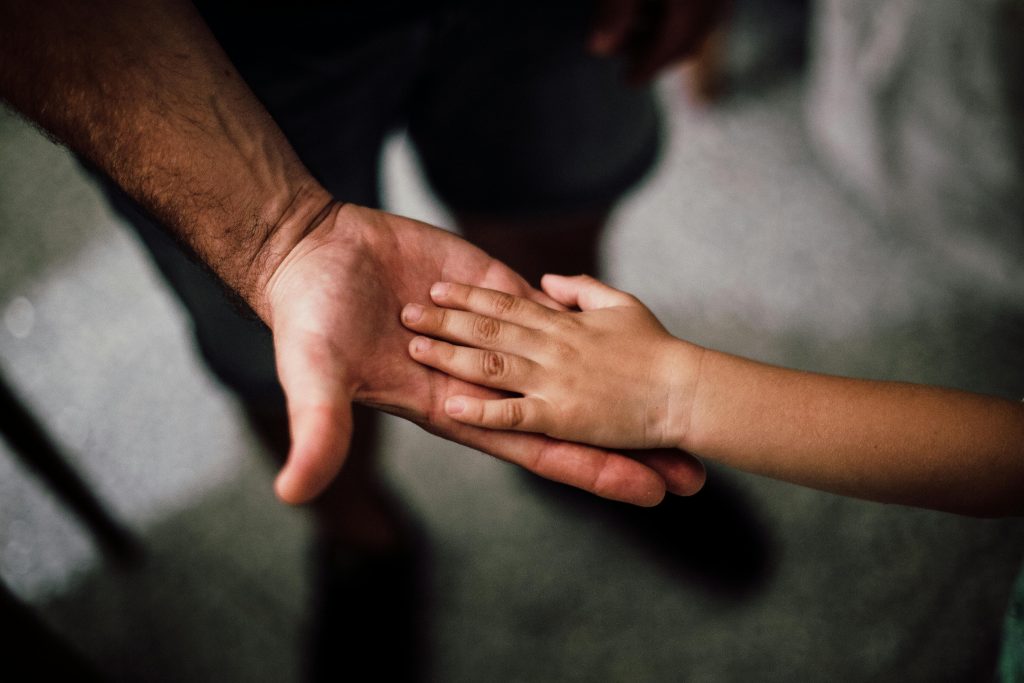 Close-up of supportive hands symbolising patron support for young people’s mental health.