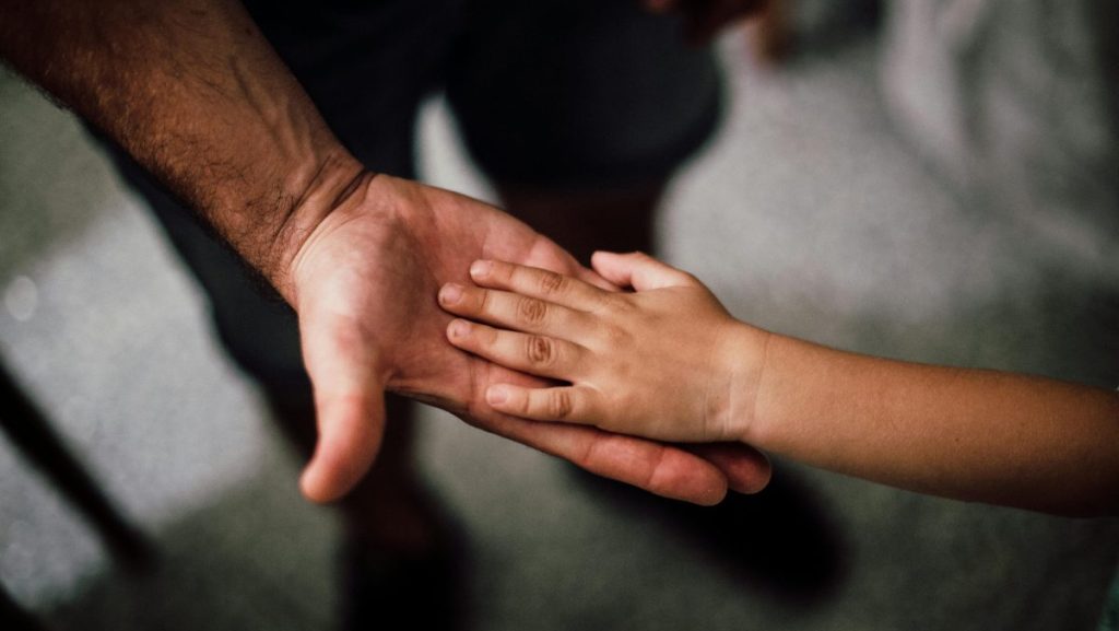 Close-up of supportive hands symbolising patron support for young people’s mental health.