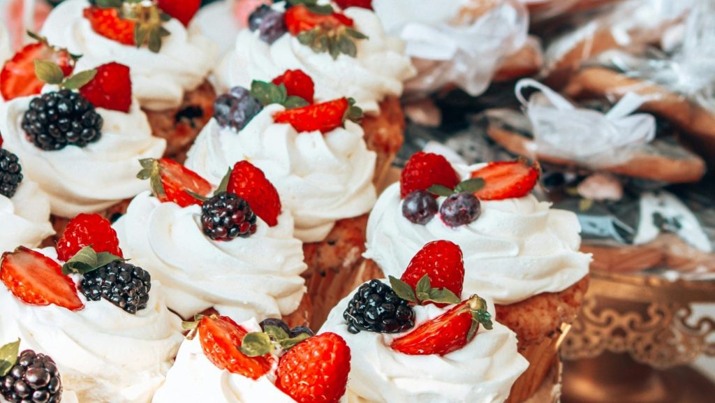 A tempting display of beautifully decorated cupcakes with fresh berries on a stand.