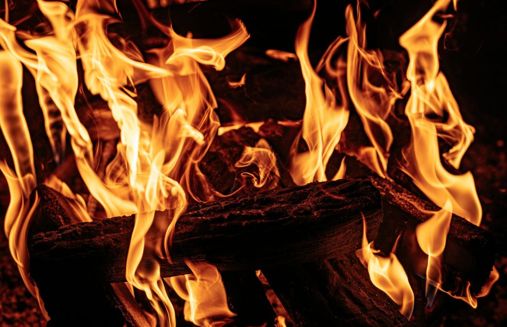 A detailed close-up of bright flames consuming wooden logs, showcasing the mesmerizing beauty of fire.